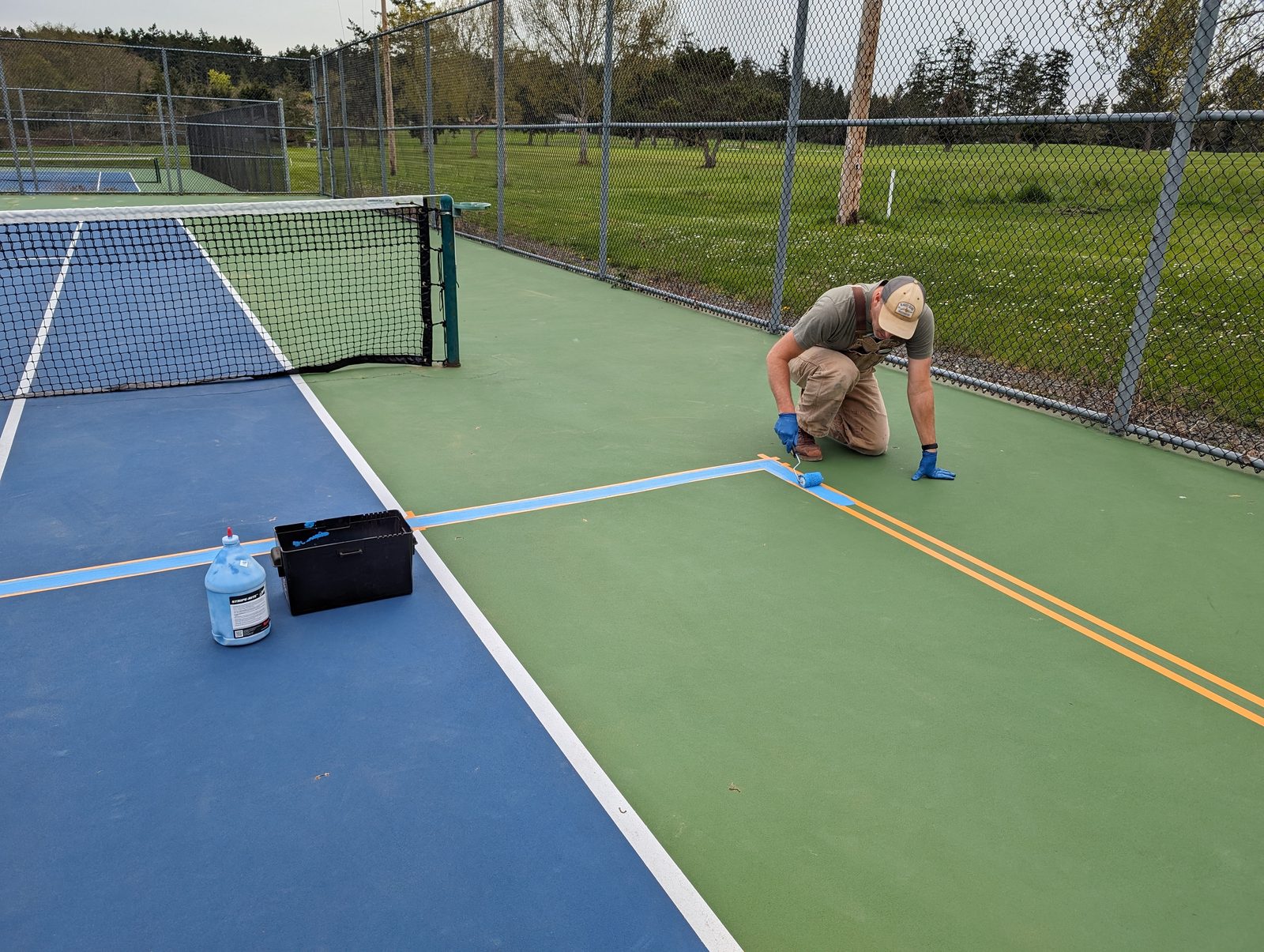 David Kane taping and striping pickleball lines on a club court