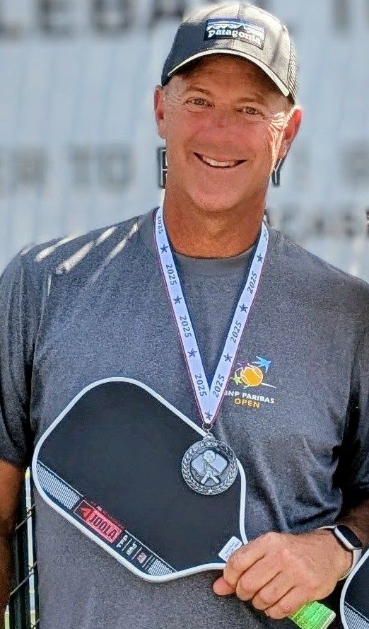 David Kane wearing a tournament medal and holding his paddle
