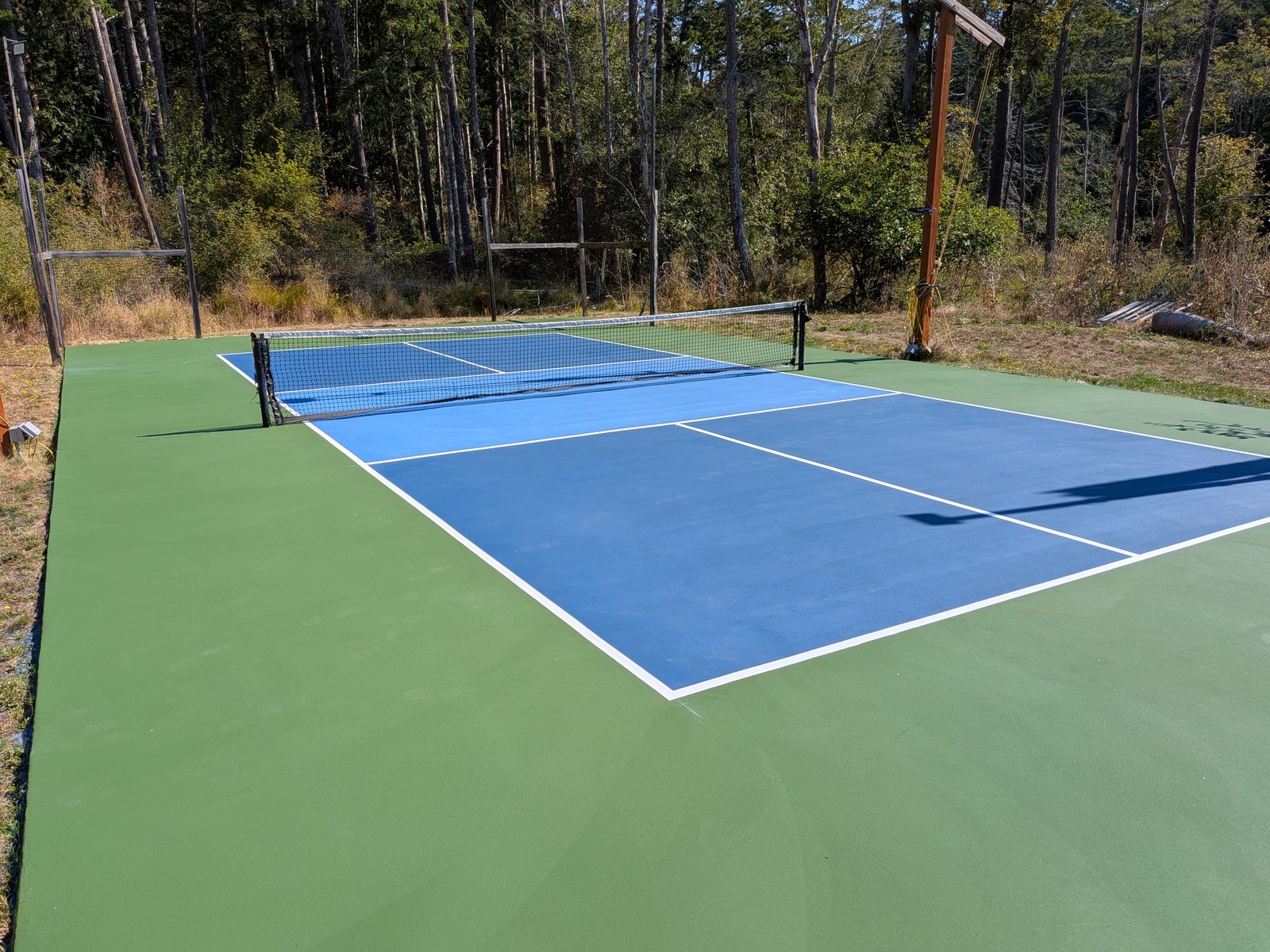 A private backyard pickleball court with a fresh blue and green surface